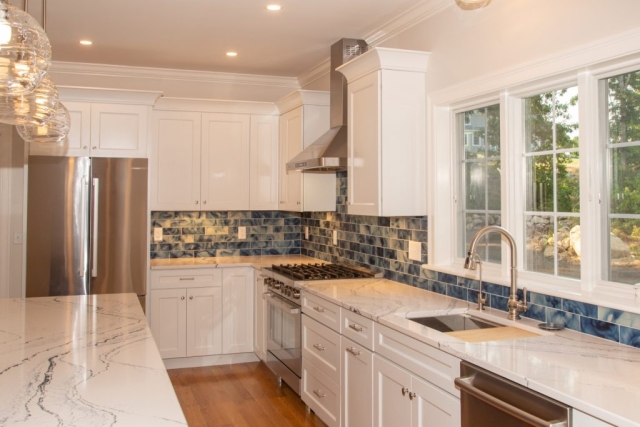 View of kitchen with stove, sink, countertops, island